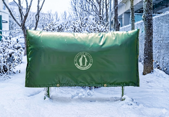 Protected backflow preventer with a green insulated Backflow Blanket in the snow
